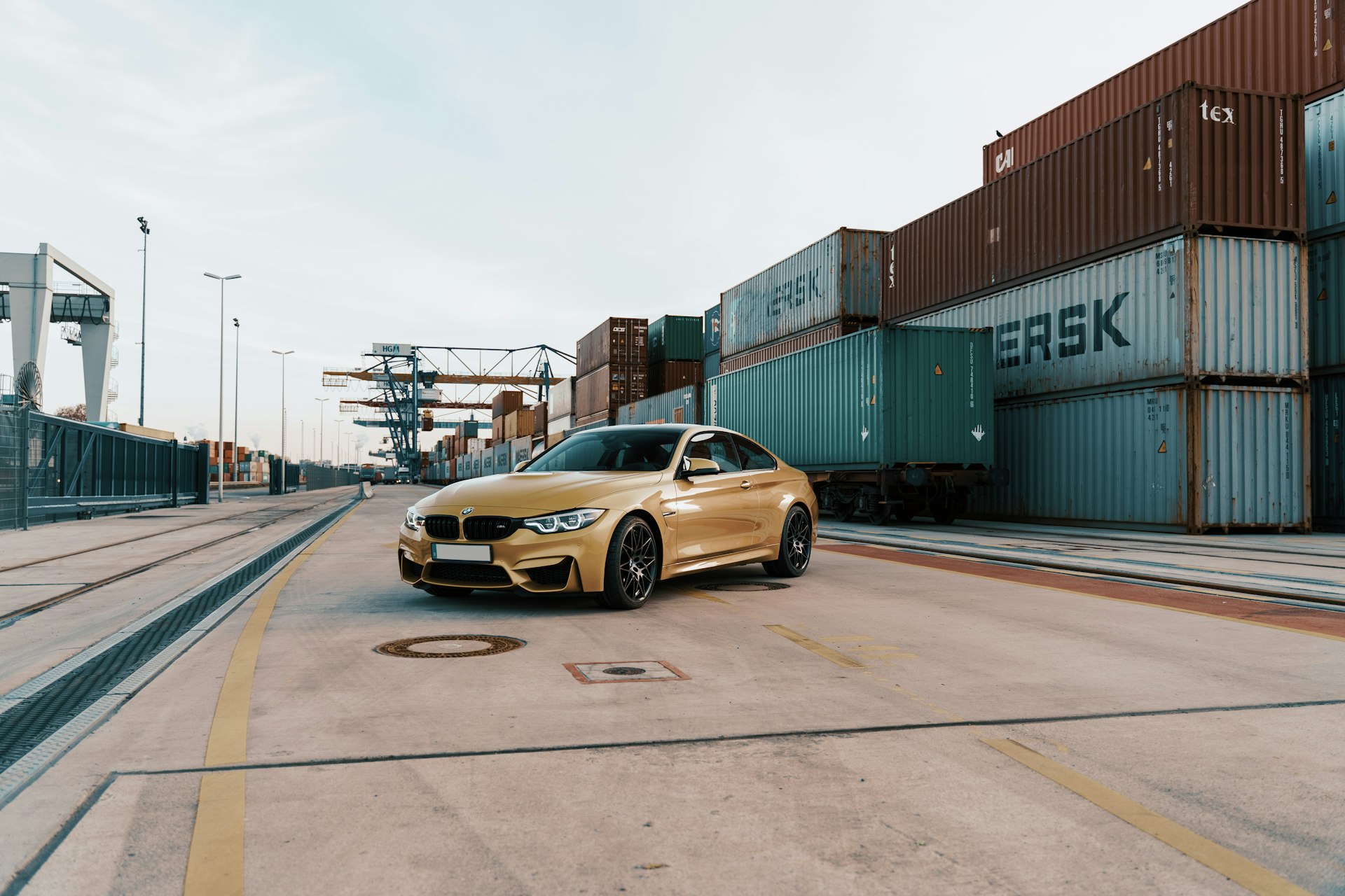 yellow BMW sedan parked near containers during daytime